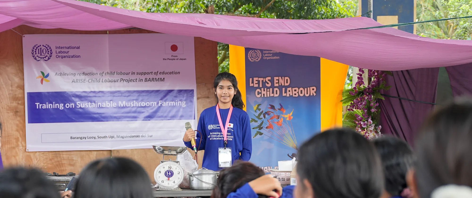 a girl speaks with child labour banners behind