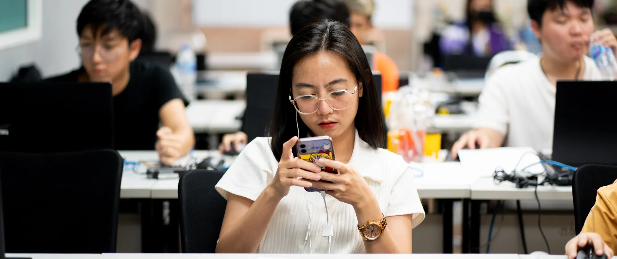 Woman looking at her phone during a digital content creator course in Bangkok
