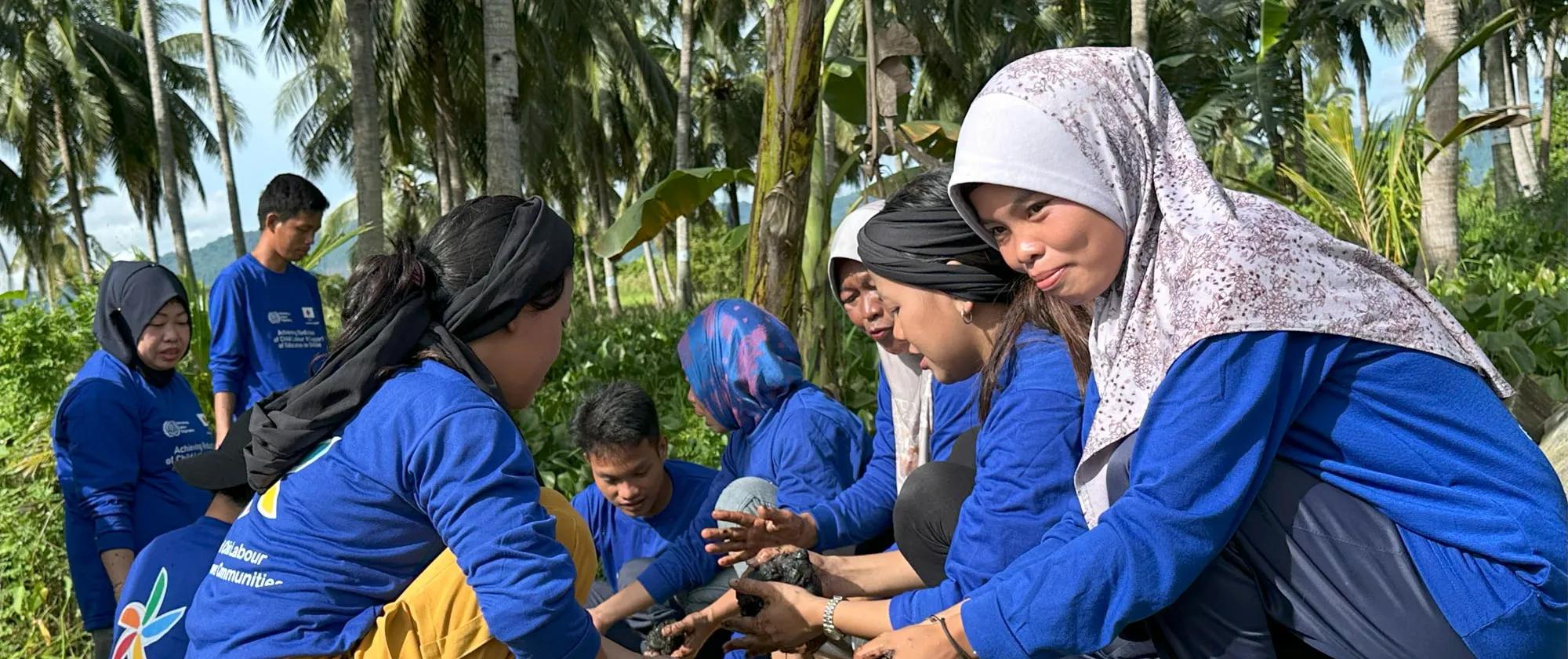 Women plant seeds behind coconut trees