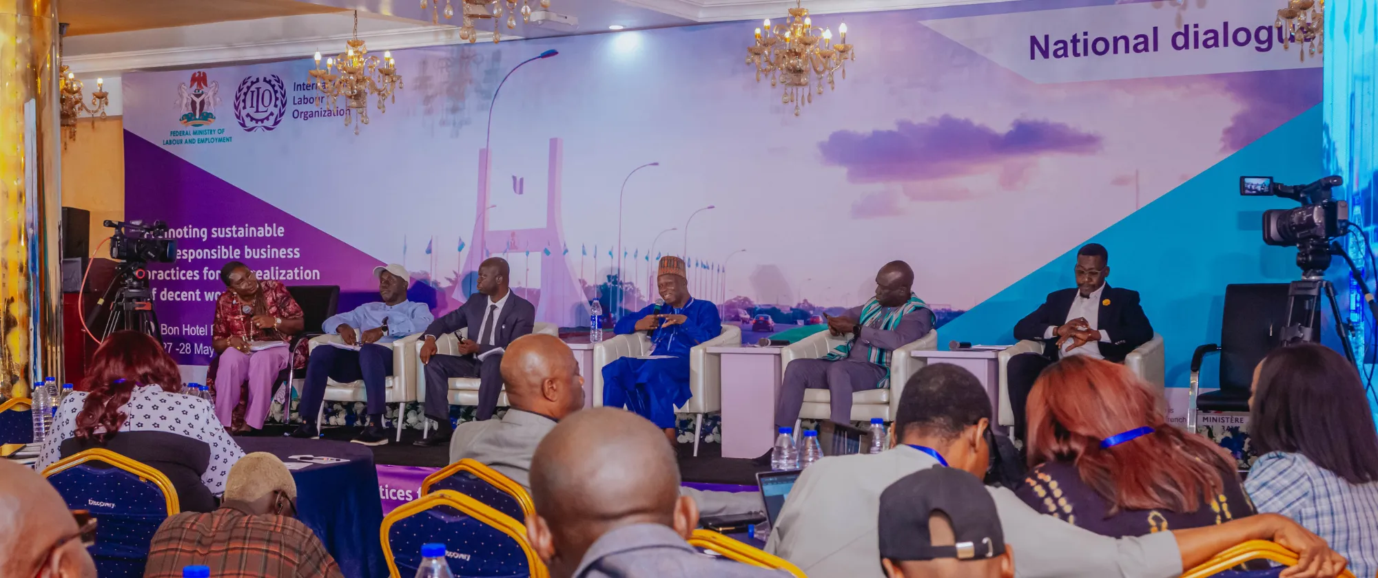 Group of panelists on stage with participants listening