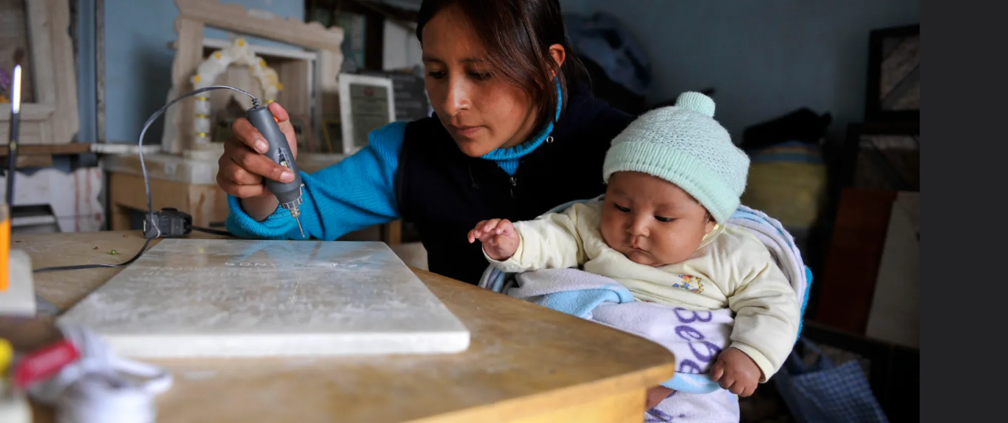 Mother carving tombstones while taking care of her baby in Potosí, Bolivia.