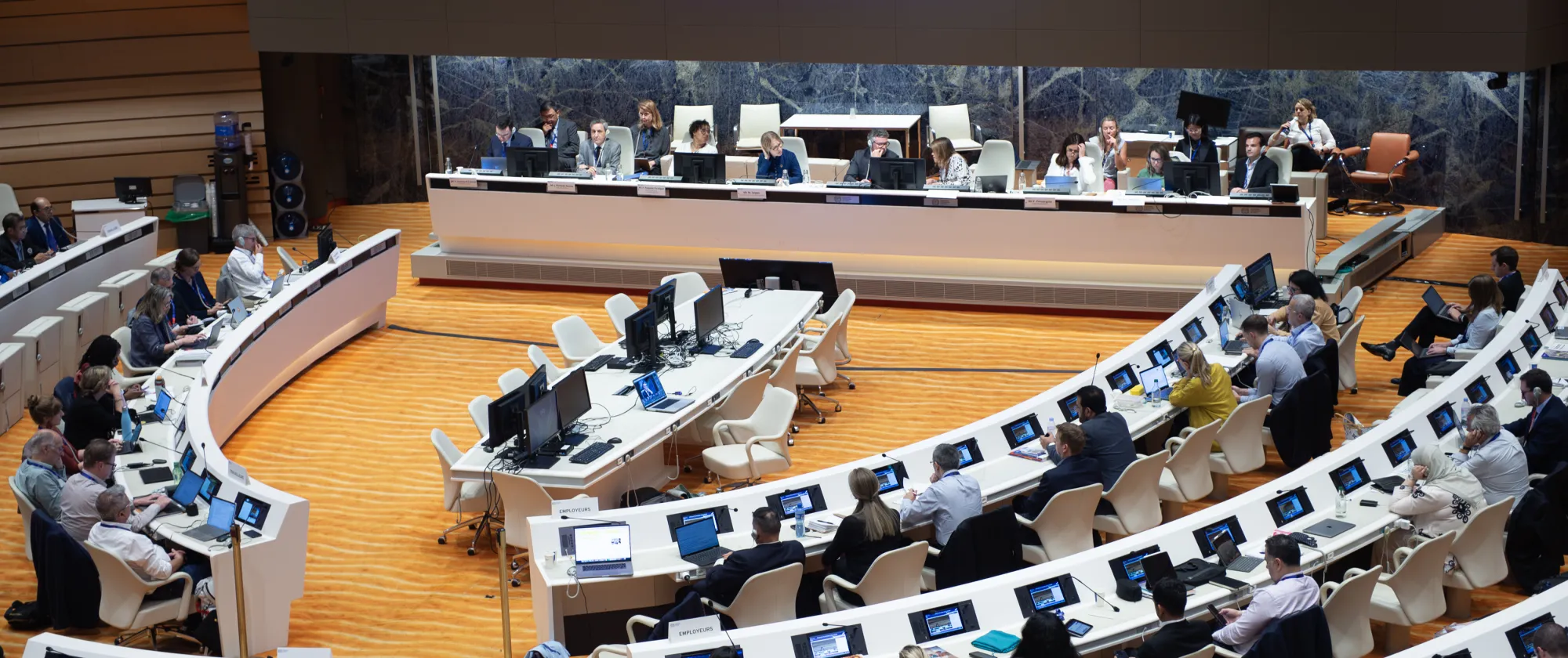 People sitting in a meeting room with a wide digital screen on the back