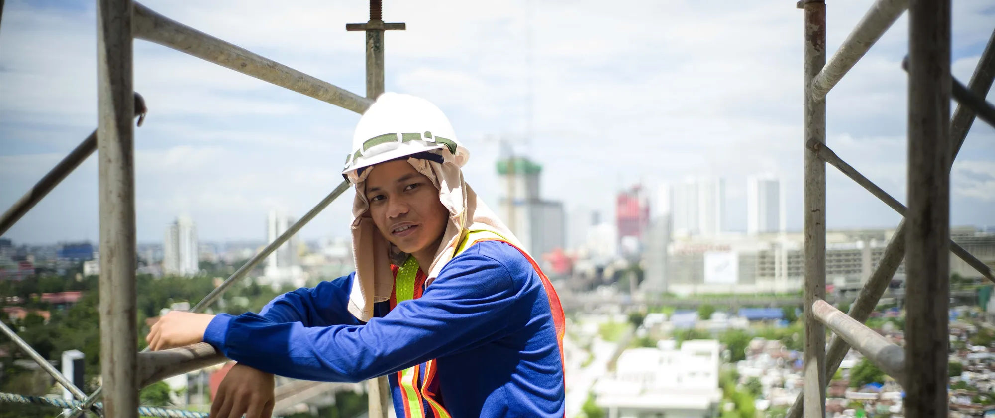 a young male construction worker wearing a hard hat on top of a building
