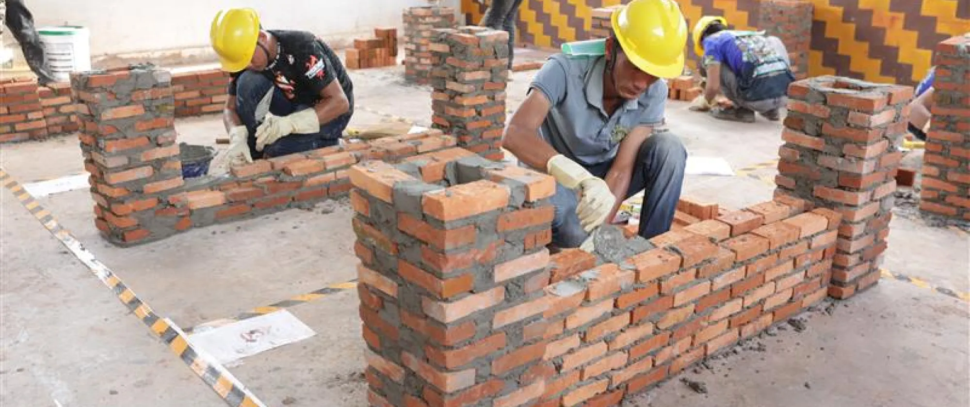 Wokers demonstarting bricklaying.