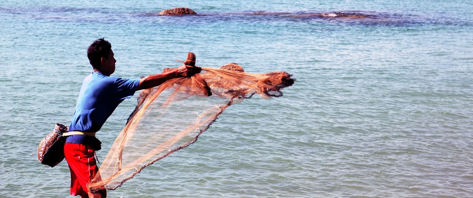 pescador lanzando red de pesca al mar