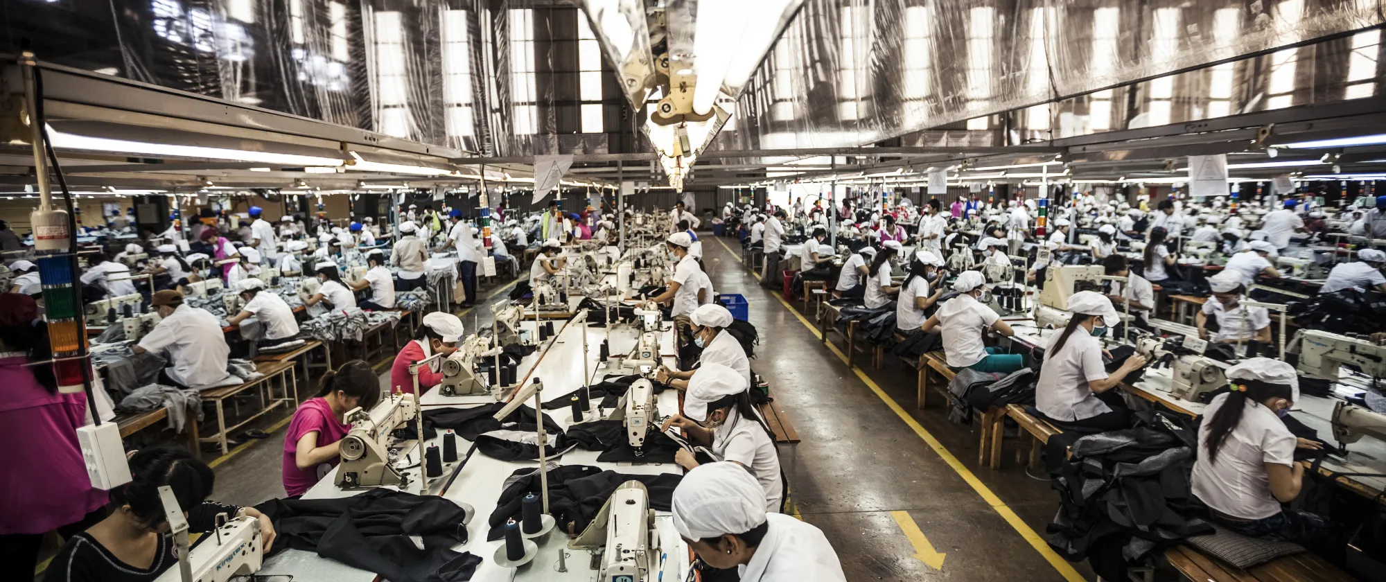 Wide shot of the garment factory featuring row of busy workers 