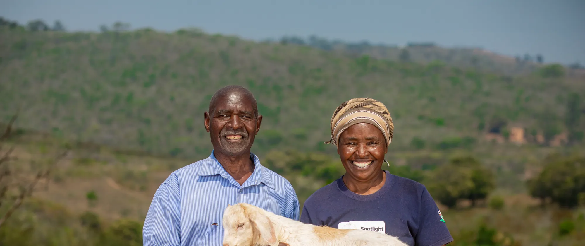 A man and a woman holding a lamb together and smiling at the camera  