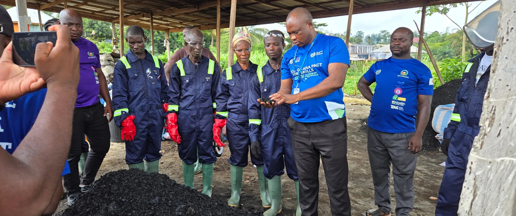 An ILO official inspecting a product with members of the community group watching