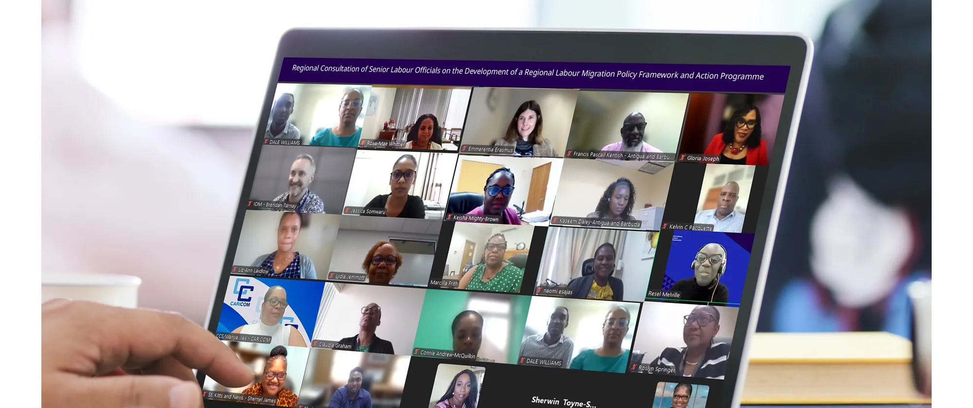 A close-up of a laptop screen showing a virtual meeting with multiple participants arranged in a grid format. The banner at the top reads: “Regional Consultation of Senior Labour Officials on the Development of a Regional Labour Migration Policy Framework and Action Programme.”