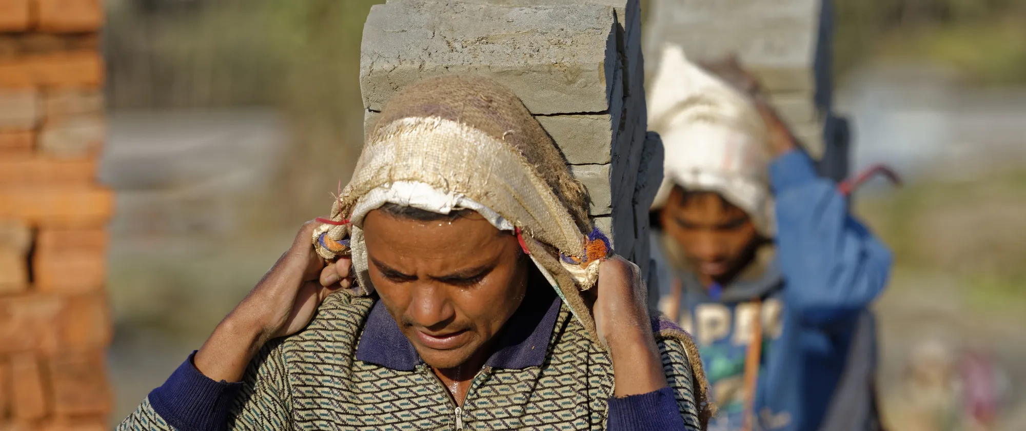 Two men carrying pieces of bricks in the suburbs of Kathmandu, Nepal.