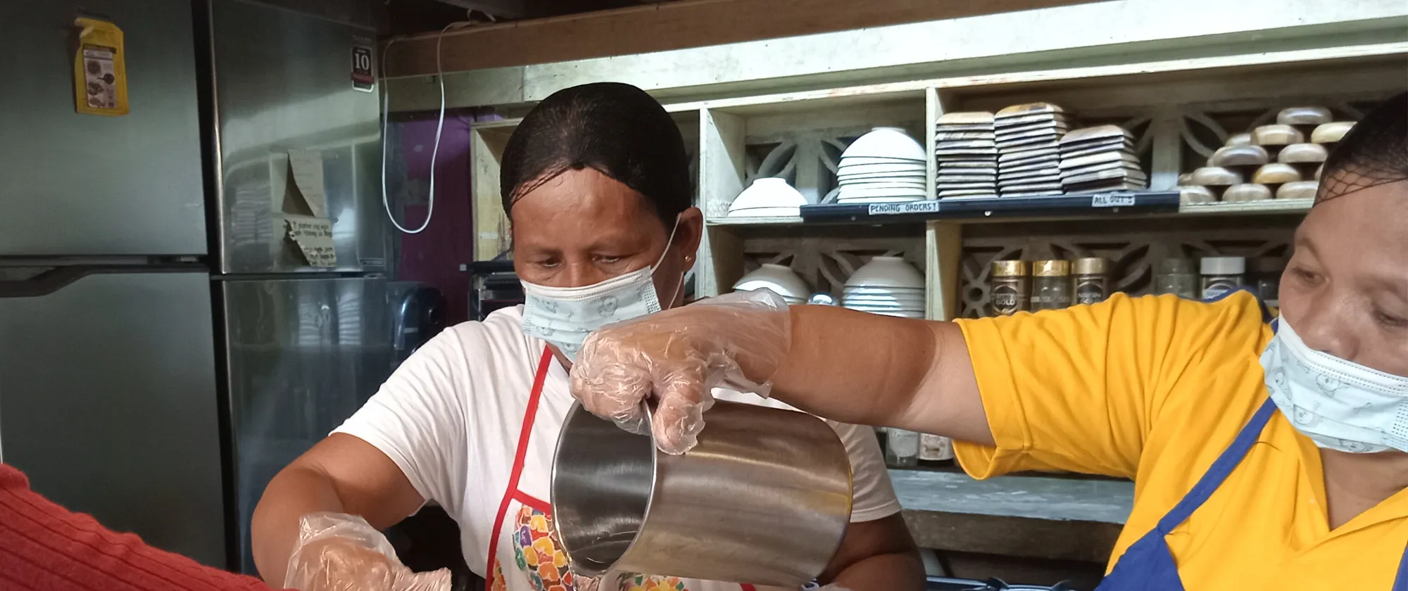 Two women cooking in a coconut culinary training.