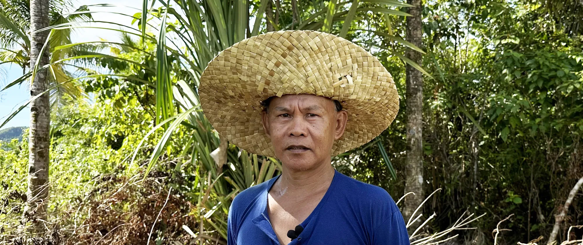 Rolly wearing a buri native hat next to a coconut tree.