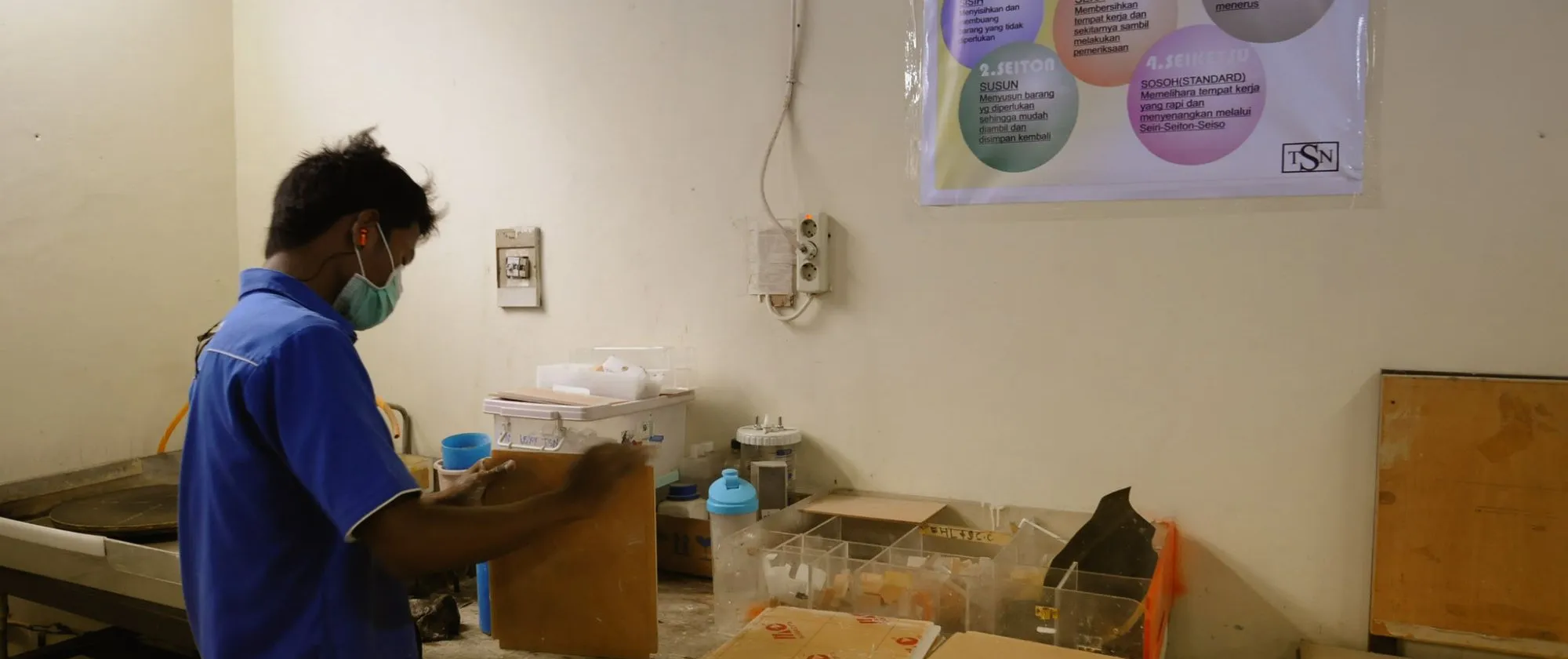 a male worker arranging his work corner with 5S poster on the wall