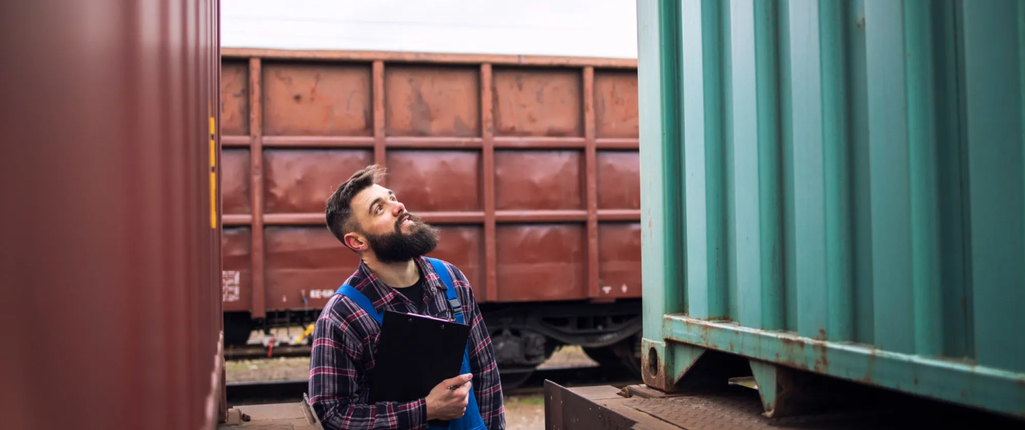 Railroad worker supervisor inspecting shipping cargo container at freight train station