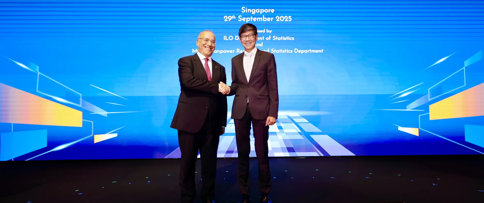 Two individuals are shaking hands on stage. 