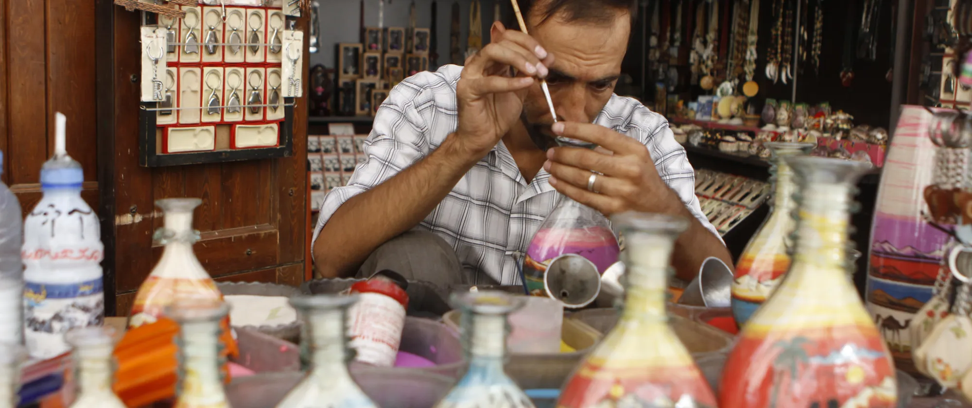 A Syrian man uses brush to paint colorful bottles