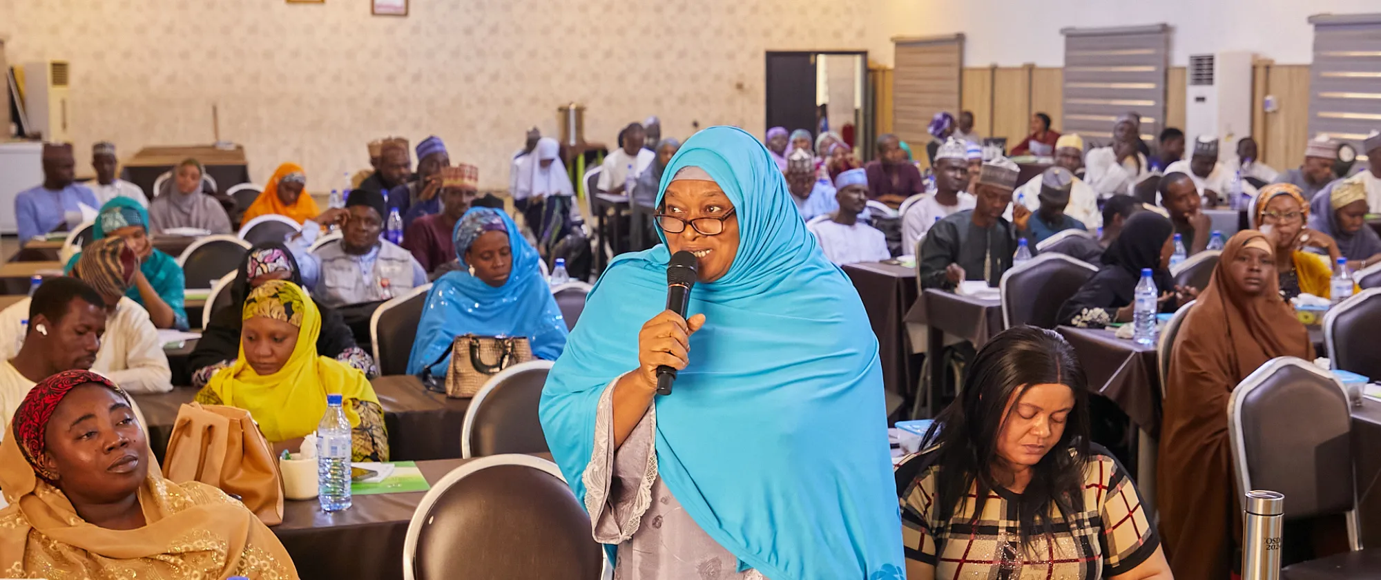 An individual addresses the room with a microphone during a plenary session