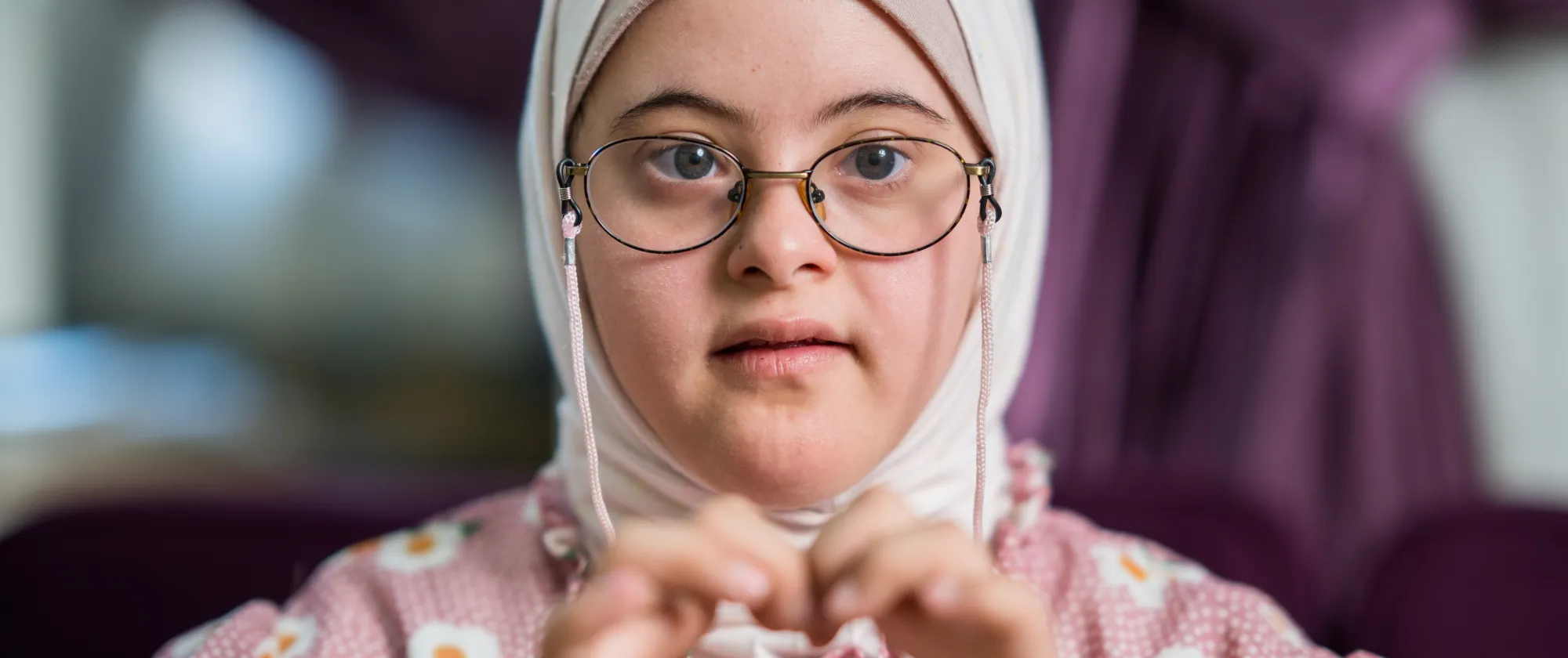 A young girl with a veil forming a heart with her hands