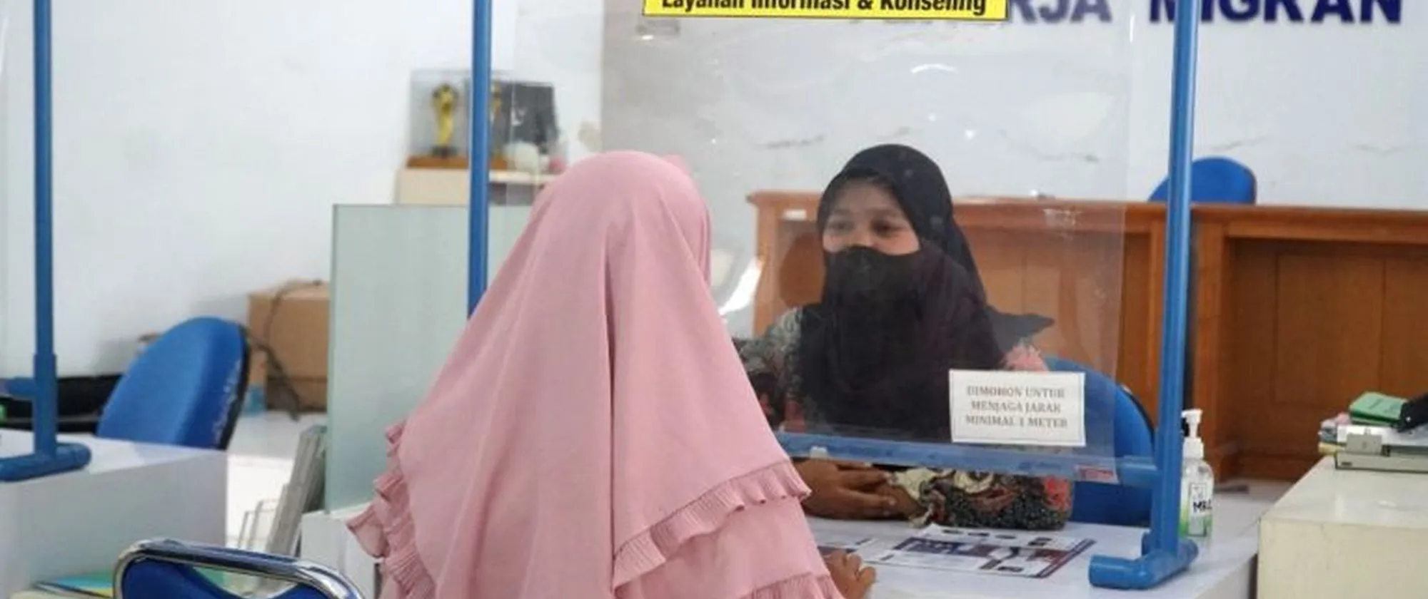 2 women with hijab sit face-to-face in an office 