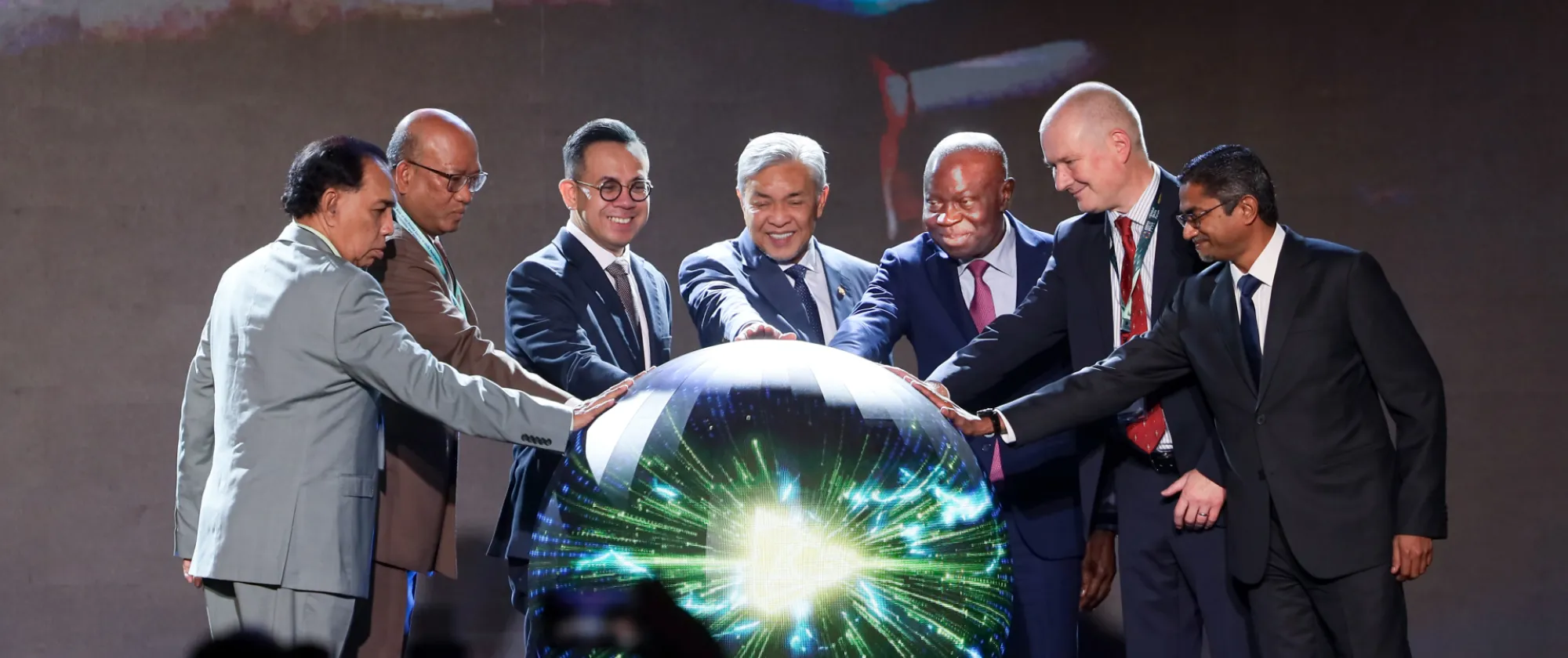 Seven formally dressed individuals simultaneously touch a model globe to inaugurate the ceremony.