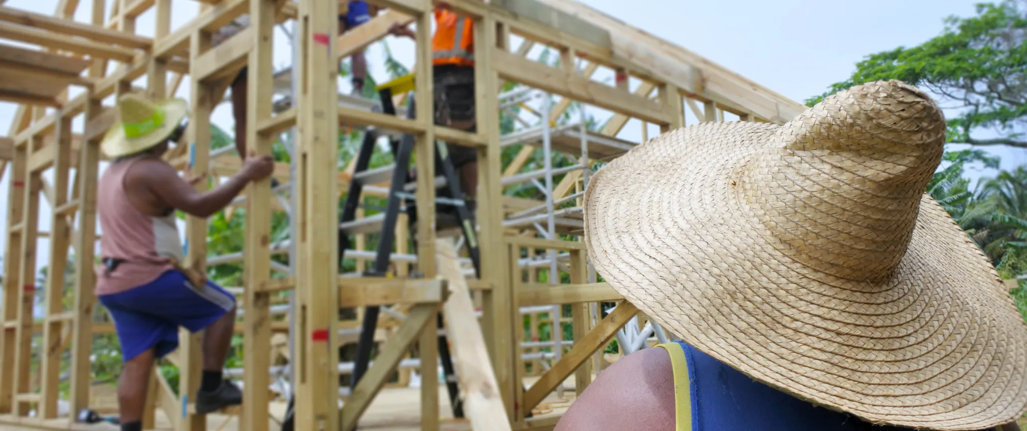 Group of unrecognizable Pacific islanders builders building a new local traditional architecture residential wooden home in Rarotonga, Cook Islands