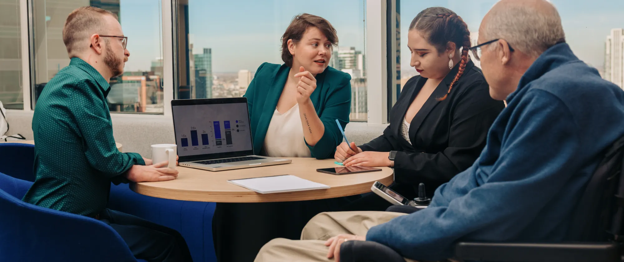 Four colleagues sitting around a table with a laptop in front of them.