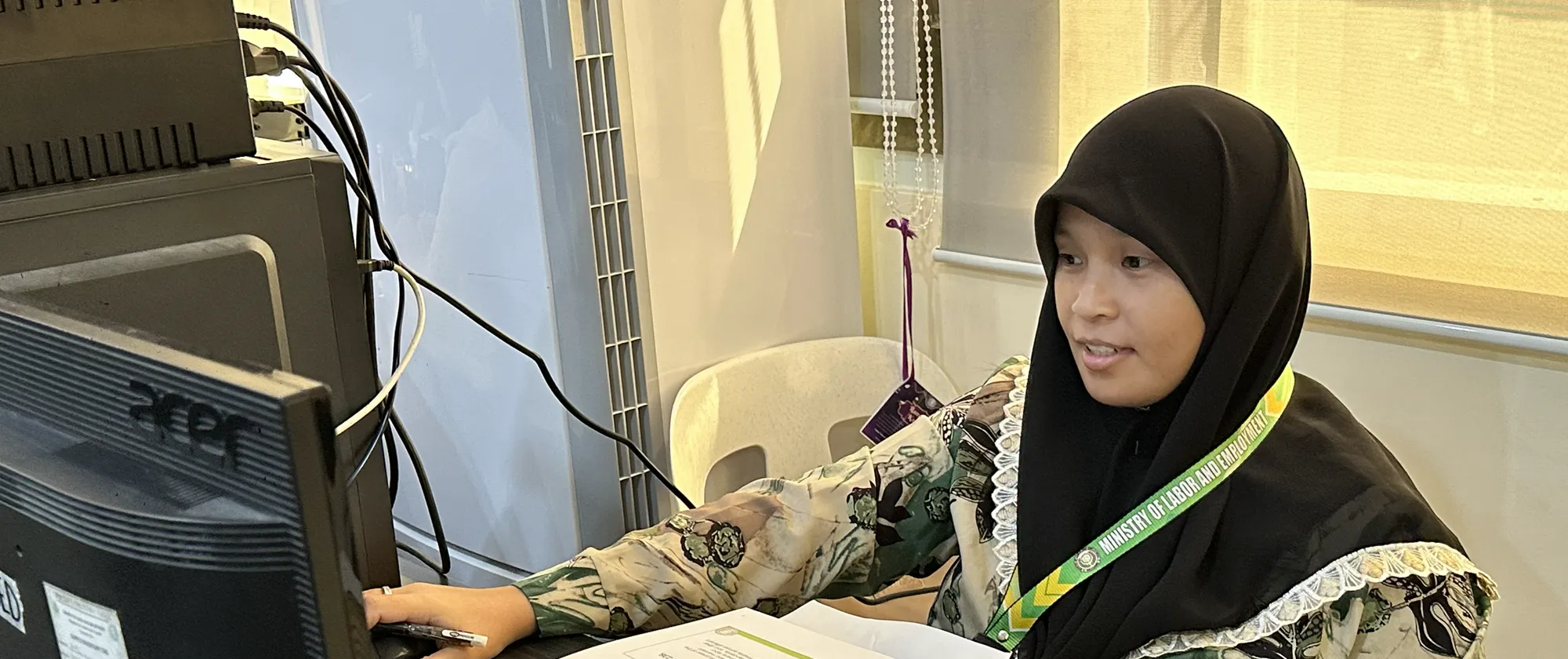 a female worker wearing a hijab and using a computer