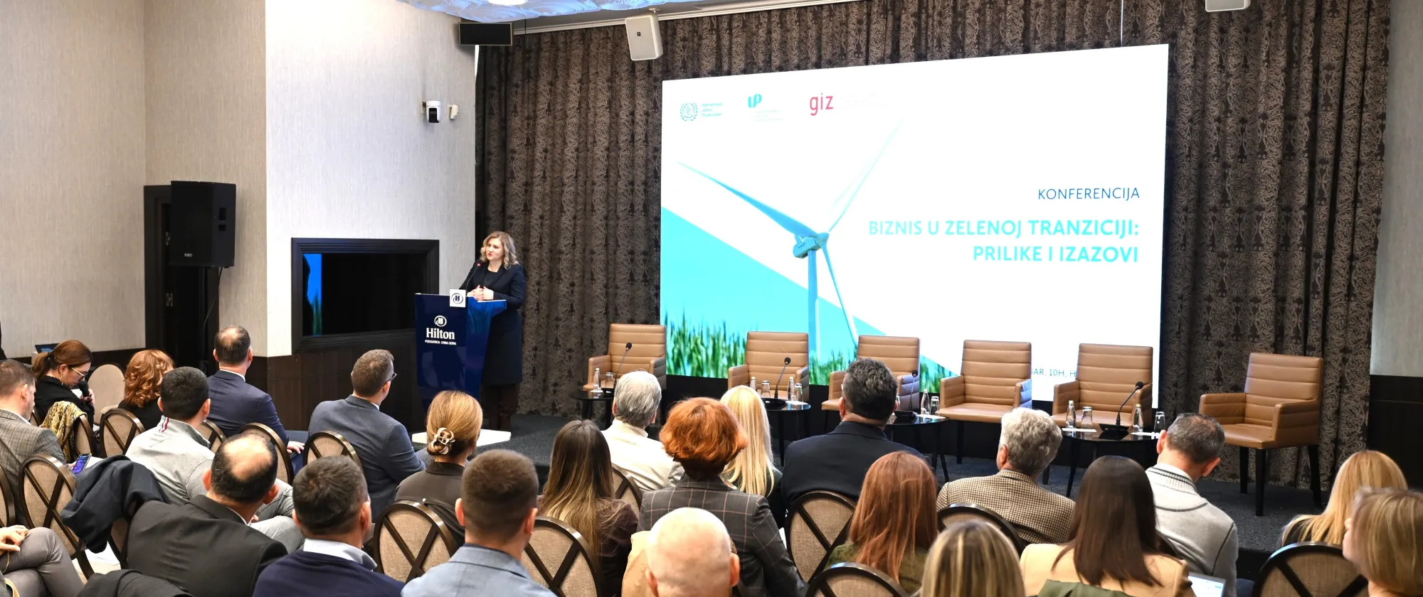 A meeting room with key note speaker Iulia Drumea - ACTEMP specialist- making a PowerPoint presentation to a full room of business representatives.