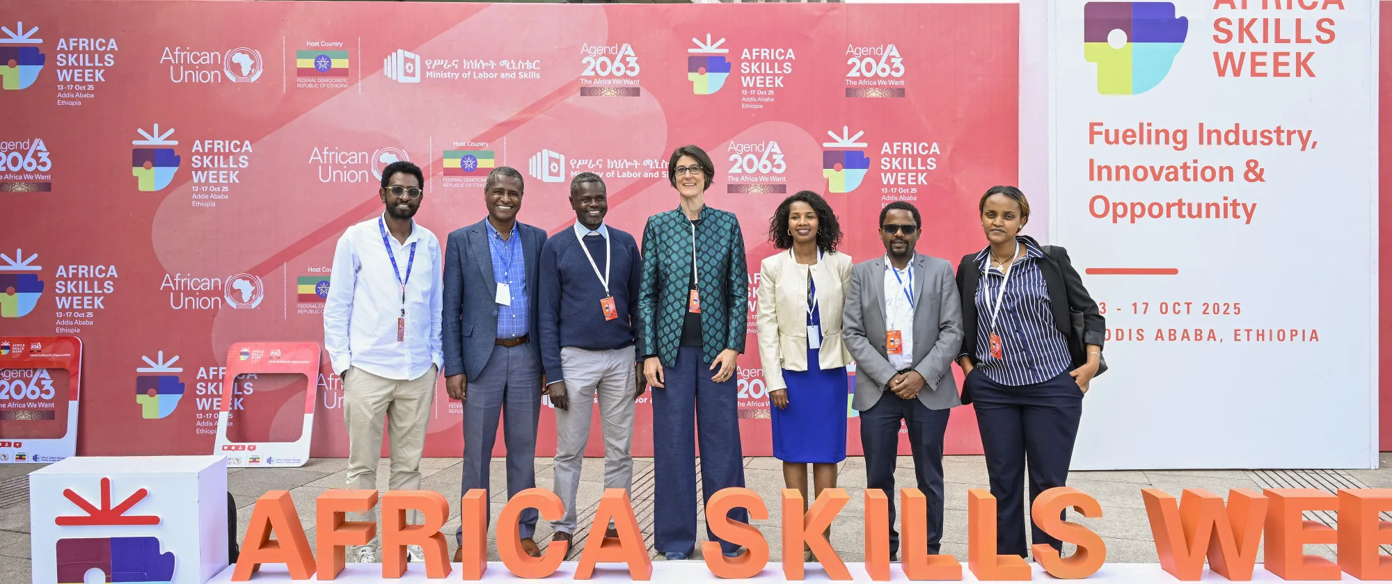 Seven members of the ILO team stand smiling in front of a red Africa Skills Week 2025 backdrop in Addis Ababa, Ethiopia.