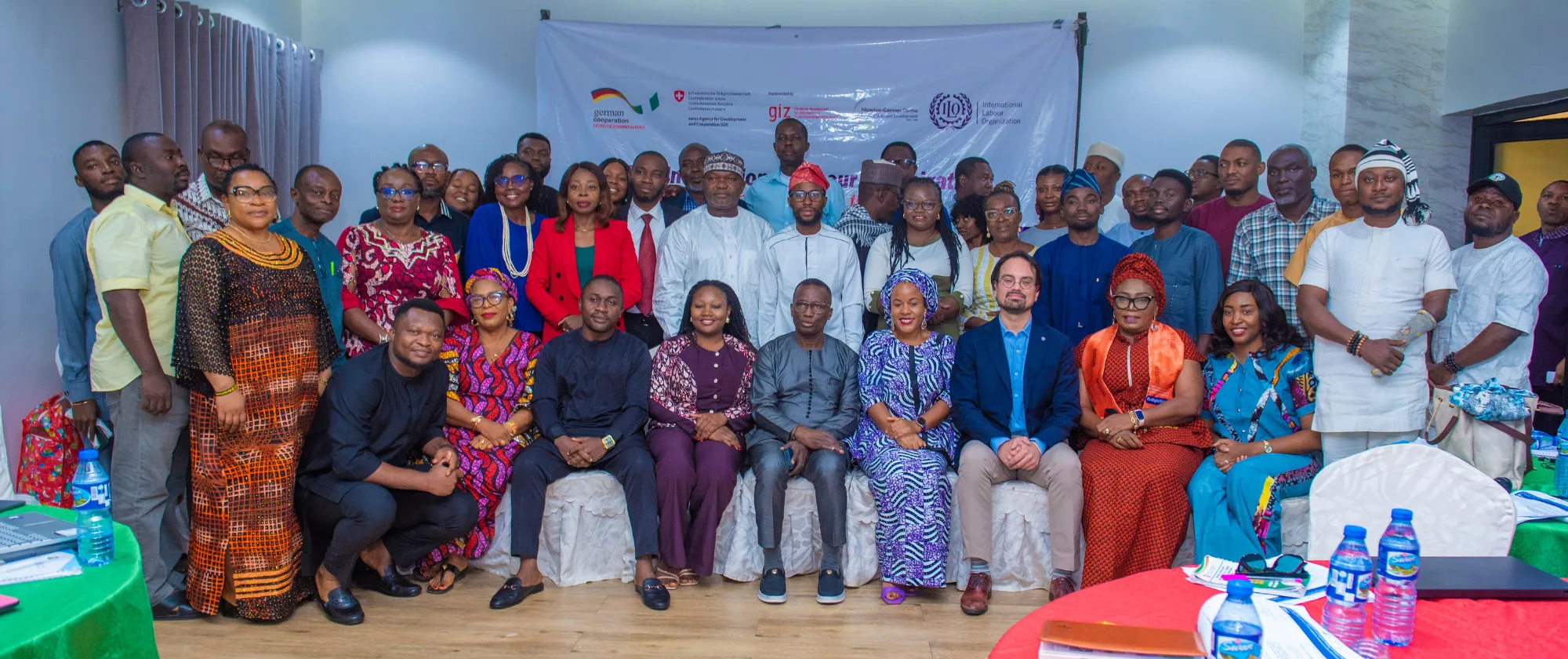 A large group of participants poses for a group photo during the ILO’s Abuja workshop on media engagement and capacity building for inclusive reporting on employment, labour migration, and decent work. The backdrop displays logos of ILO and partner organizations.