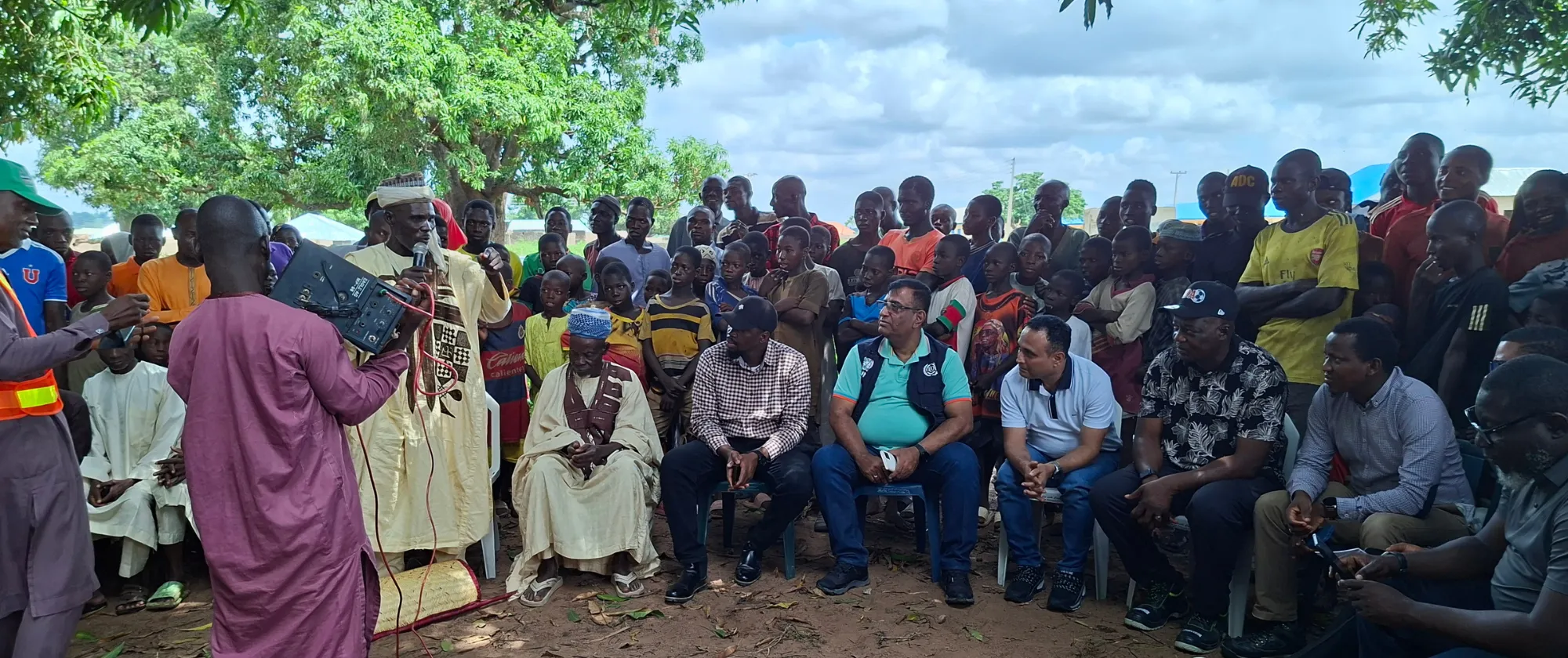 Community members and project officials gather under a tree in Niger State for an engagement session on rural road maintenance
