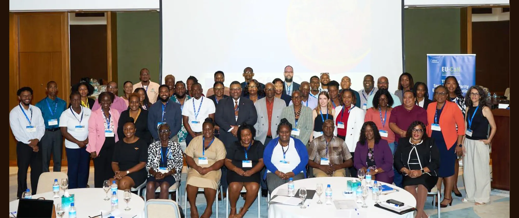 A large group of workshop participants, men and women of diverse ages pose together for a group photo in a conference room