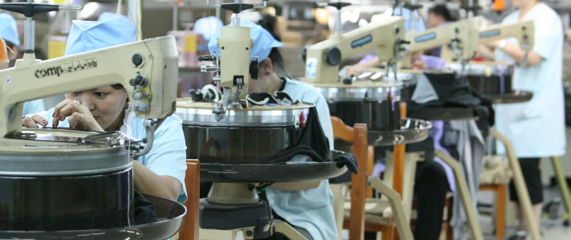 Garment workers assembling clothing using industrial sewing machines at a garment factory in Mongolia.