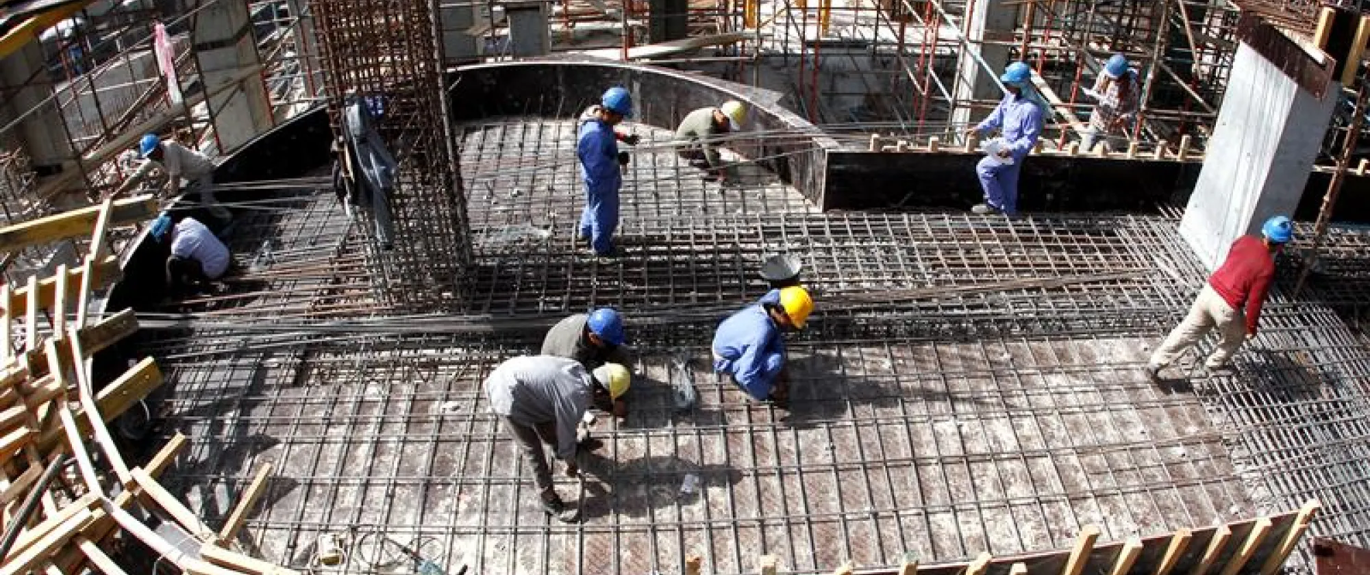 Migrant workers lay down supporting rods for a floor at a construction site in Doha Qatar.