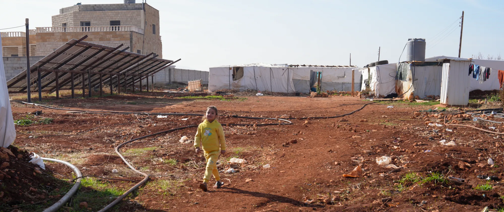Young Syrian girl Amena walks in the informal tent settlement where she lives with her family in the Bekaa Valley, a few metres from the fields where they work, 22 December 2025. 