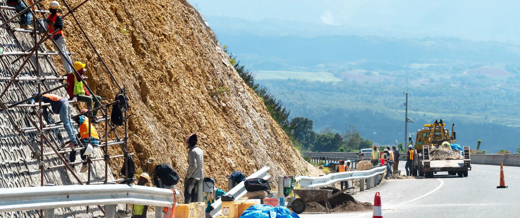 Engineers and other workers constructing anti-landslide concrete wall on a highway in Jamaica. 
