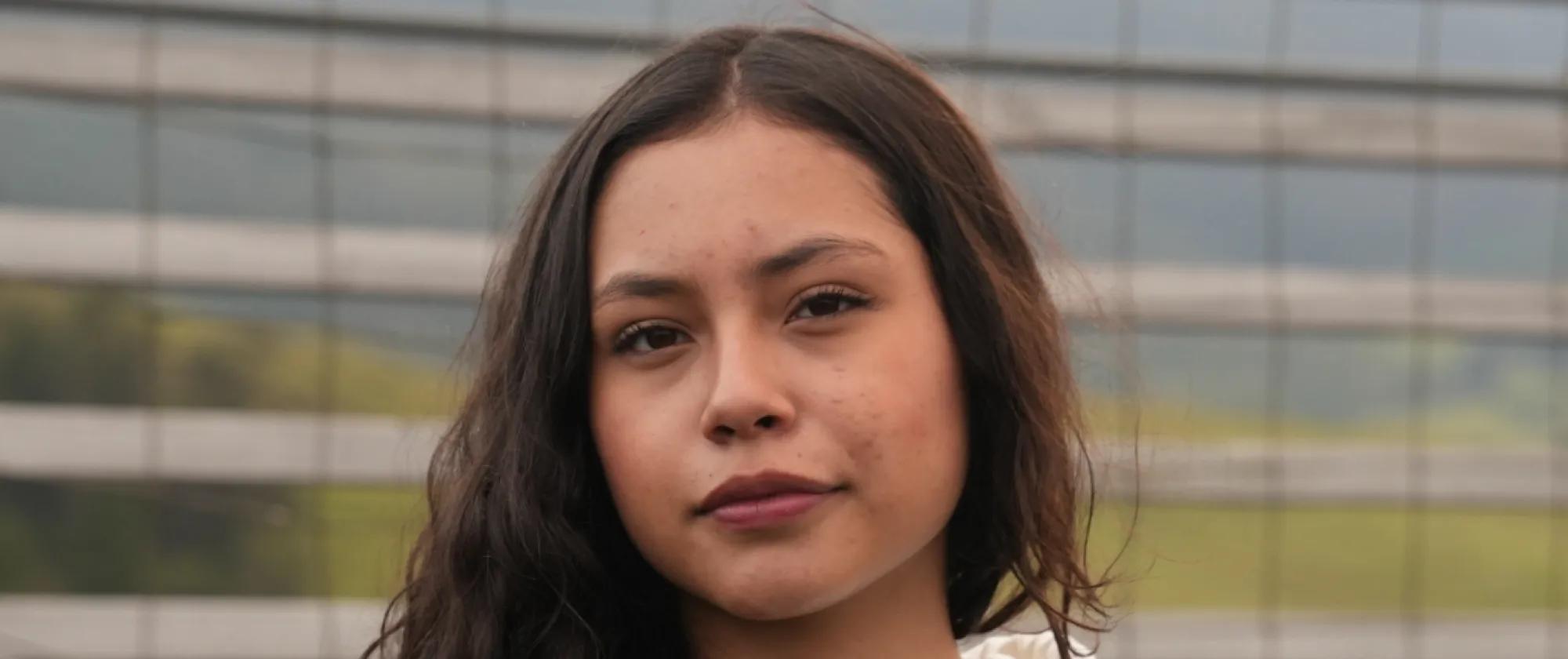 Mujer joven de cabello castaño con tez trigueña de pie en un campo de fútbol