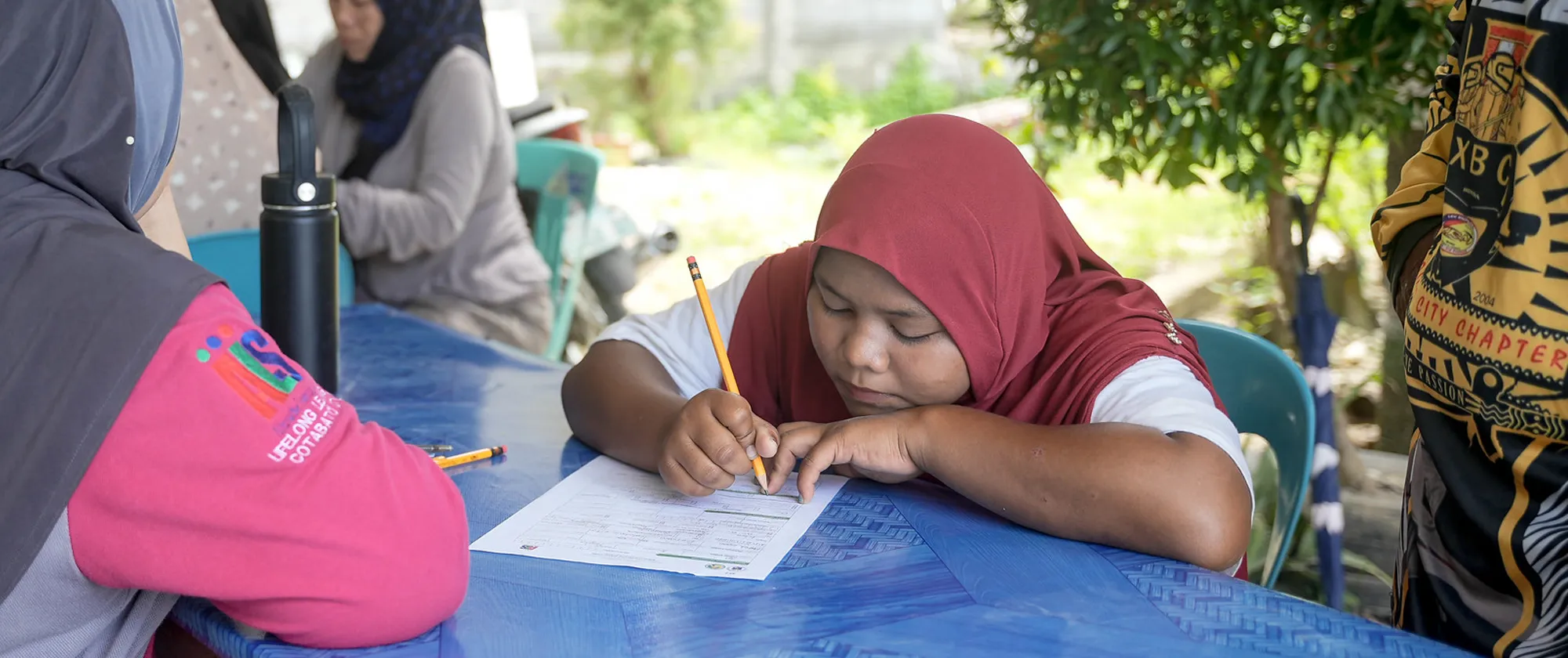 child wearing hijab and writing on a paper