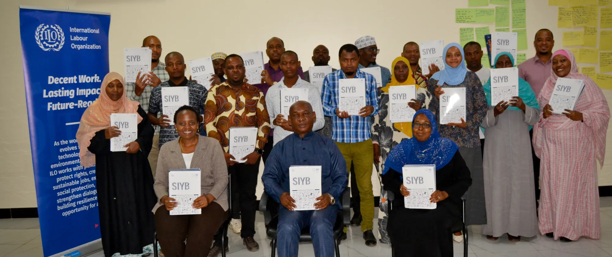 Participants of the entrepreneurship training display their Start and Improve Your Business (SIYB) training manuals during a session organized under the Zanzibar Joint Programme, supported by the ILO.