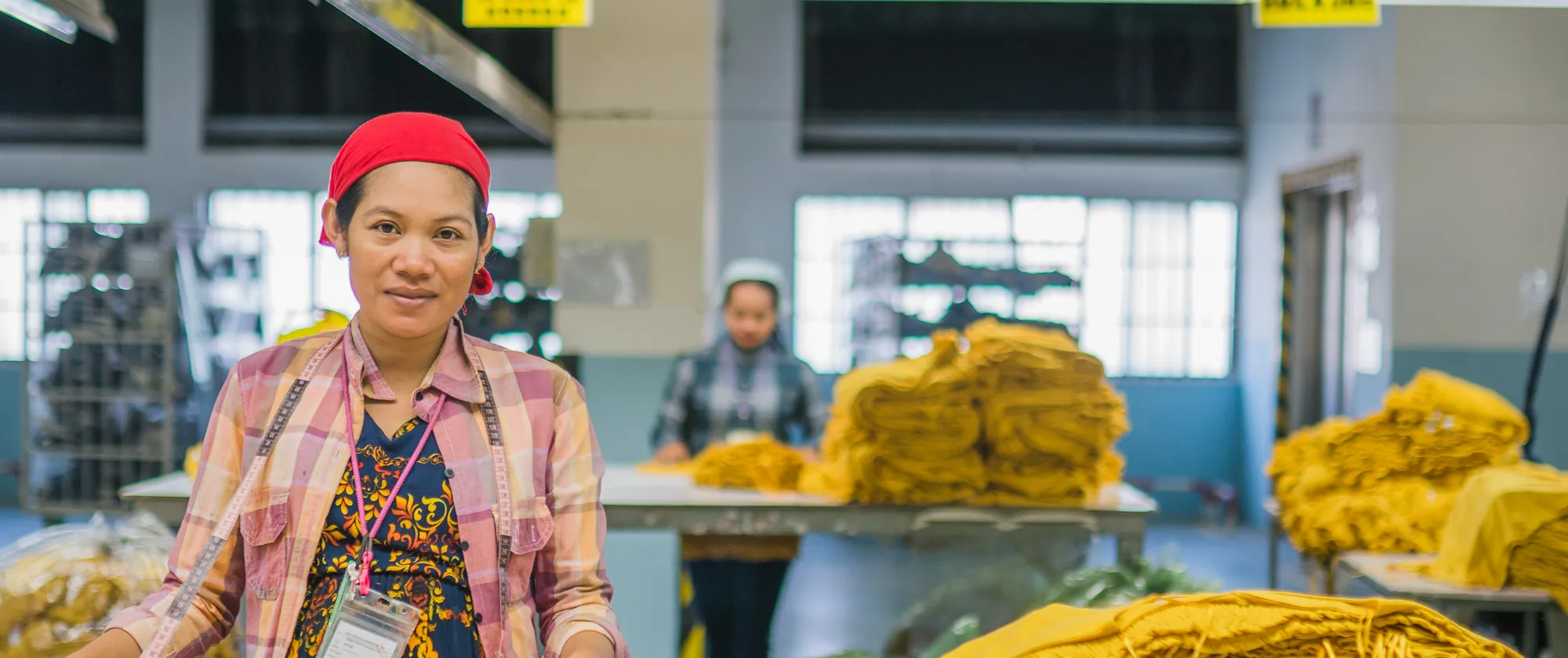 Female workers fold garments piled on worktables.