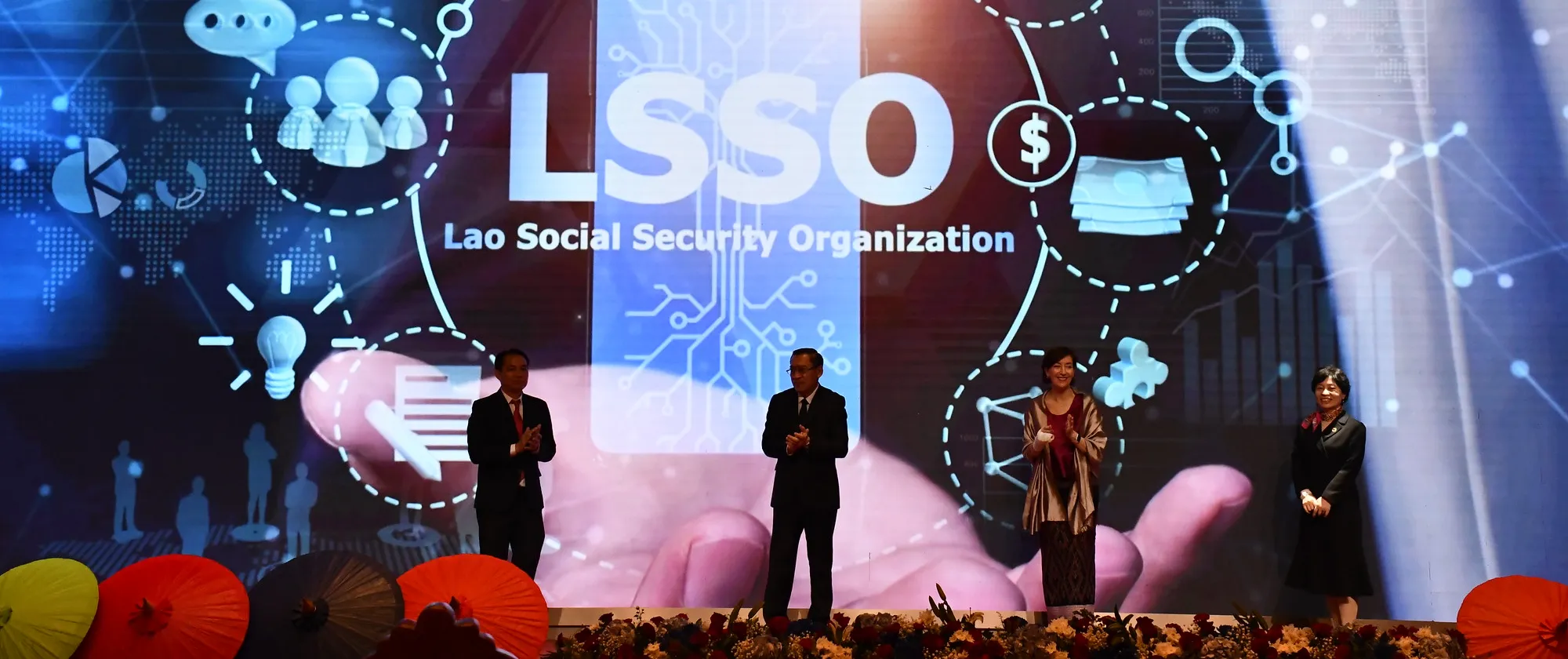 Dignitaries stand on a stage in front of a digital screen during the event.