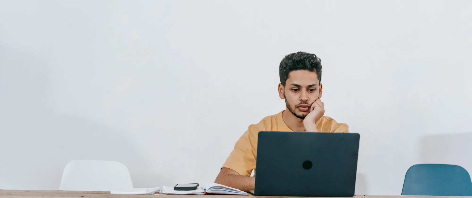 A young man sitting on a table with a laptop