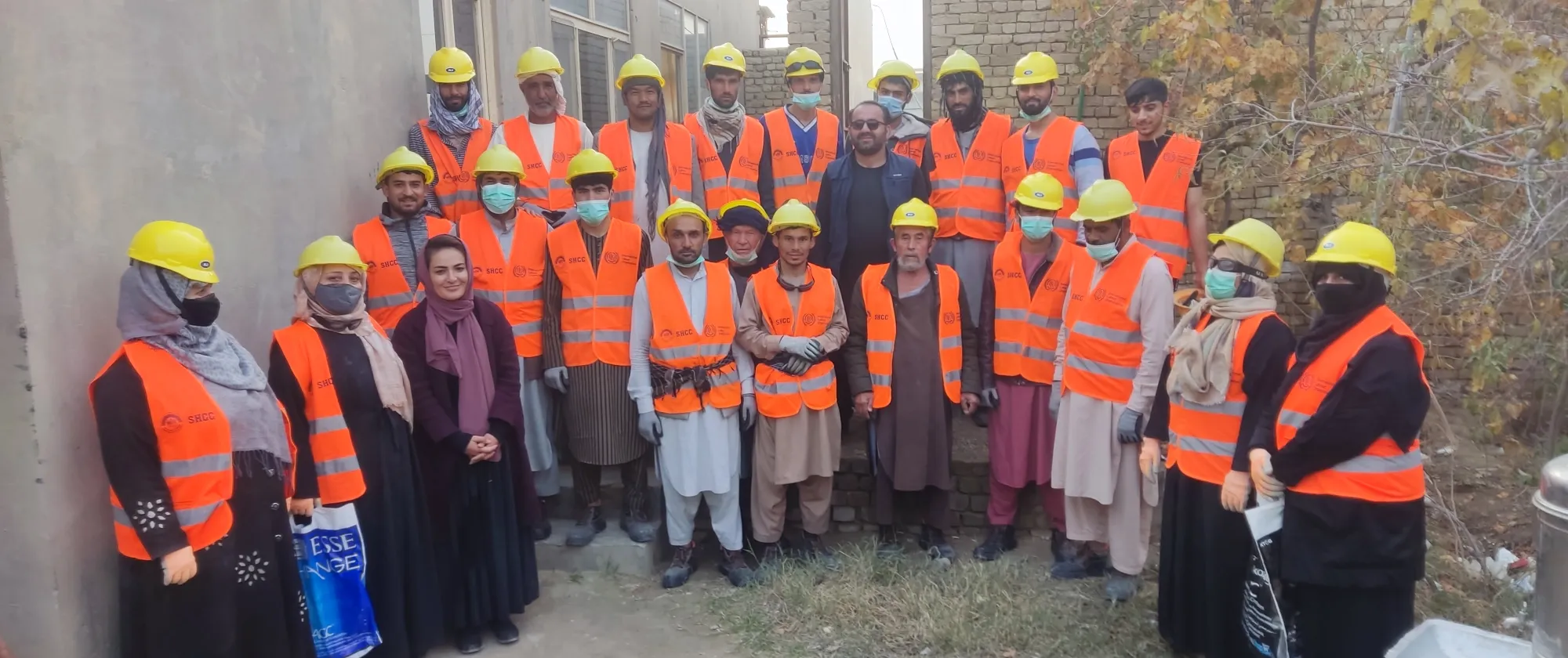 Group photo of infrastructure workers wearing orange vests and yellow helmets