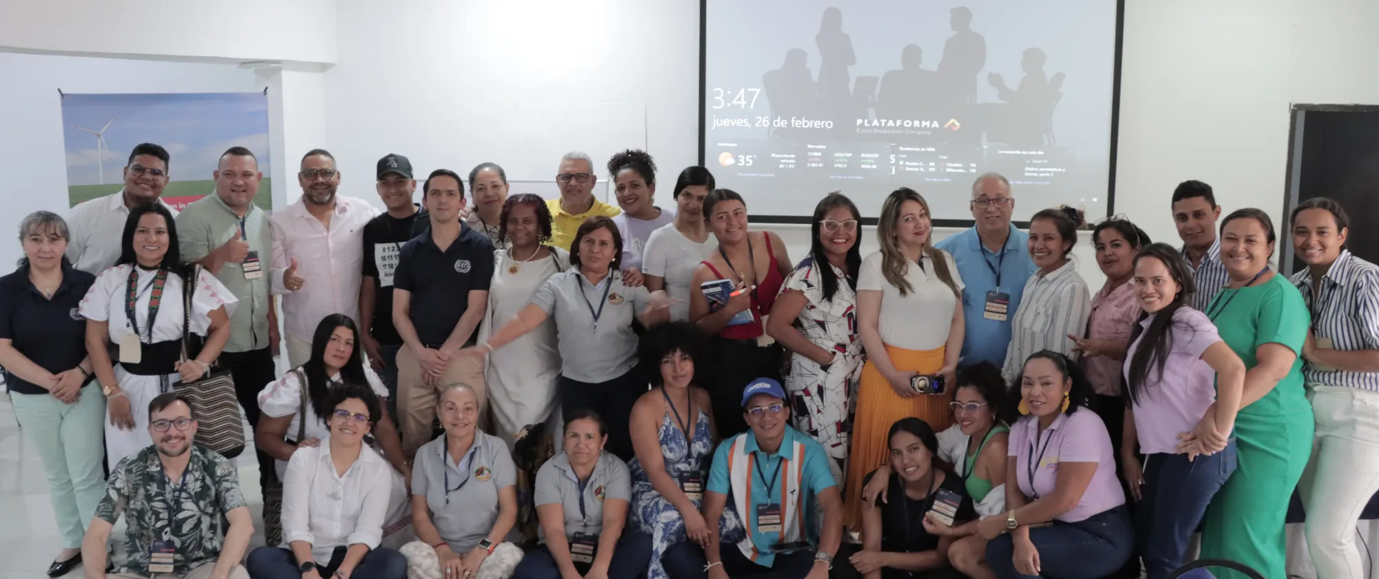 Grupo numeroso de personas posando para una foto grupal en un salon 
