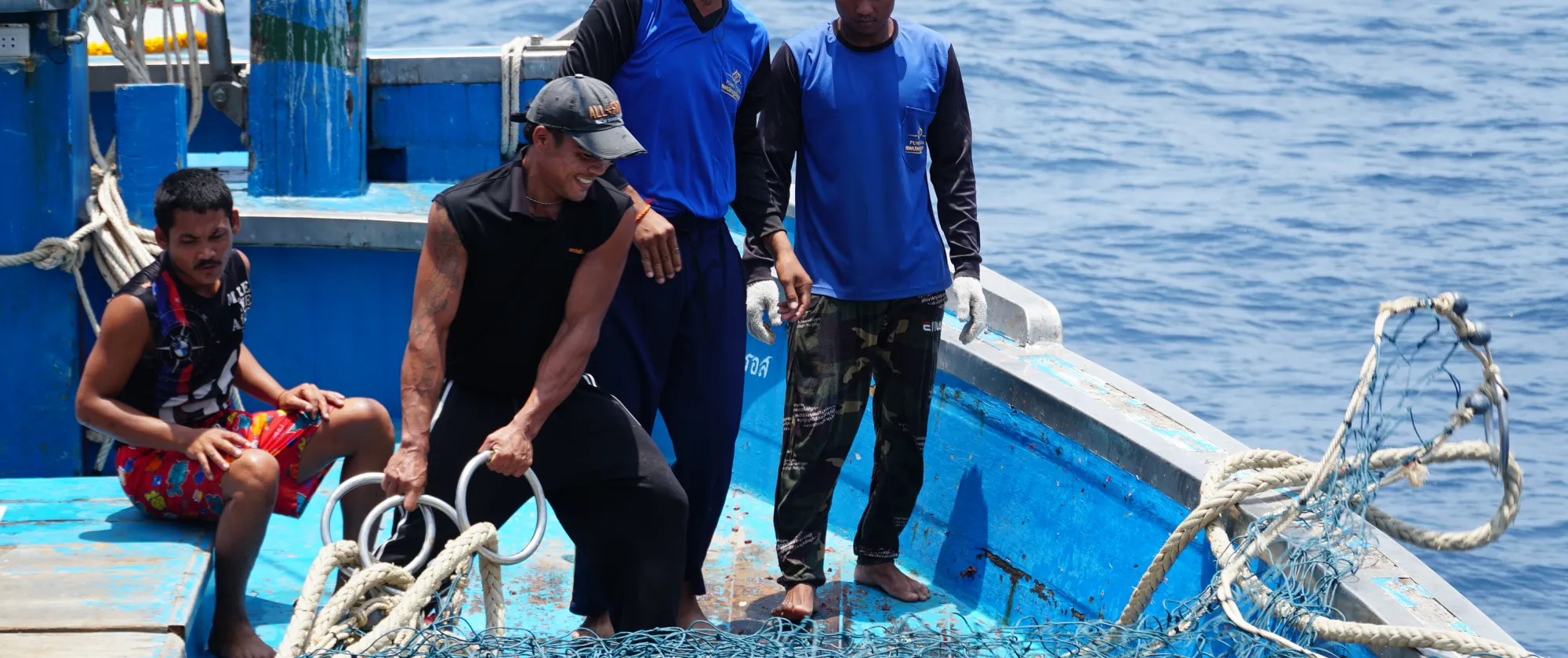 4 young fishers on a boat, working with ropes and nets, Rayong, Thailand 2023