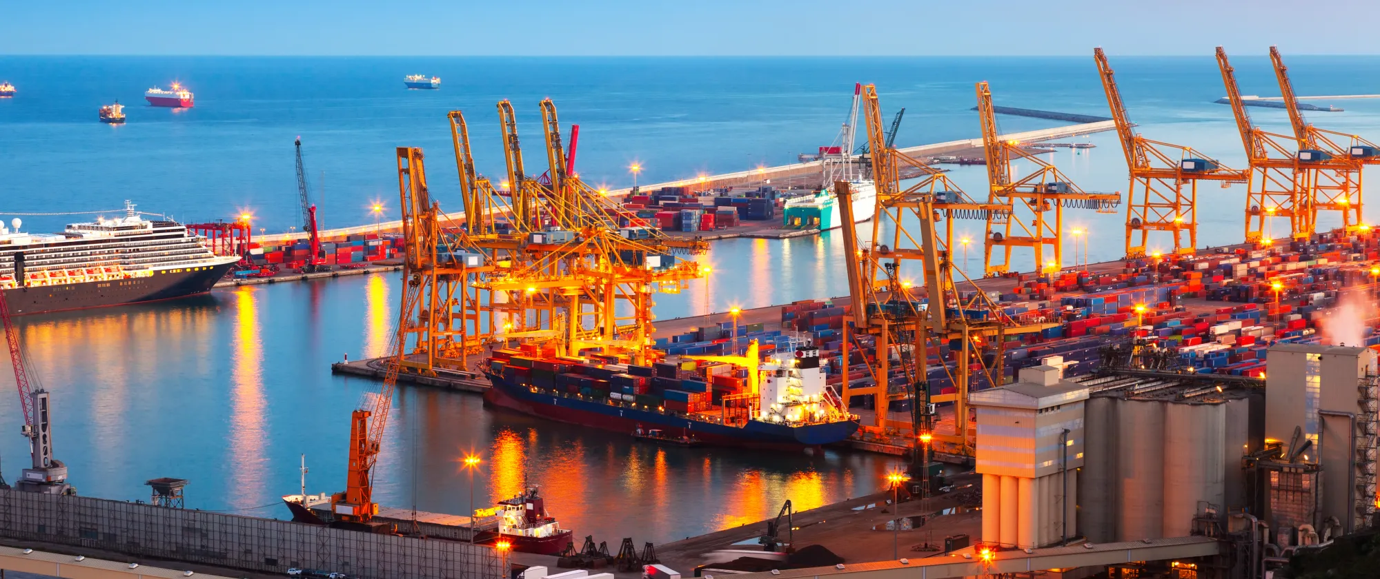 Industrial port of Barcelona, displaying container cranes, containers, ships - evening shot