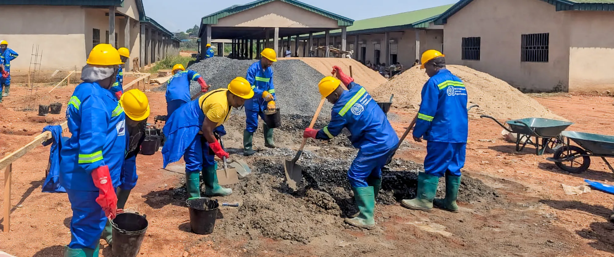 Female trainees at the Bamenda 3 training worksite mix mortar for the starter pillars of a market shed as part of an International Labour Organization youth employability project in Cameroon.