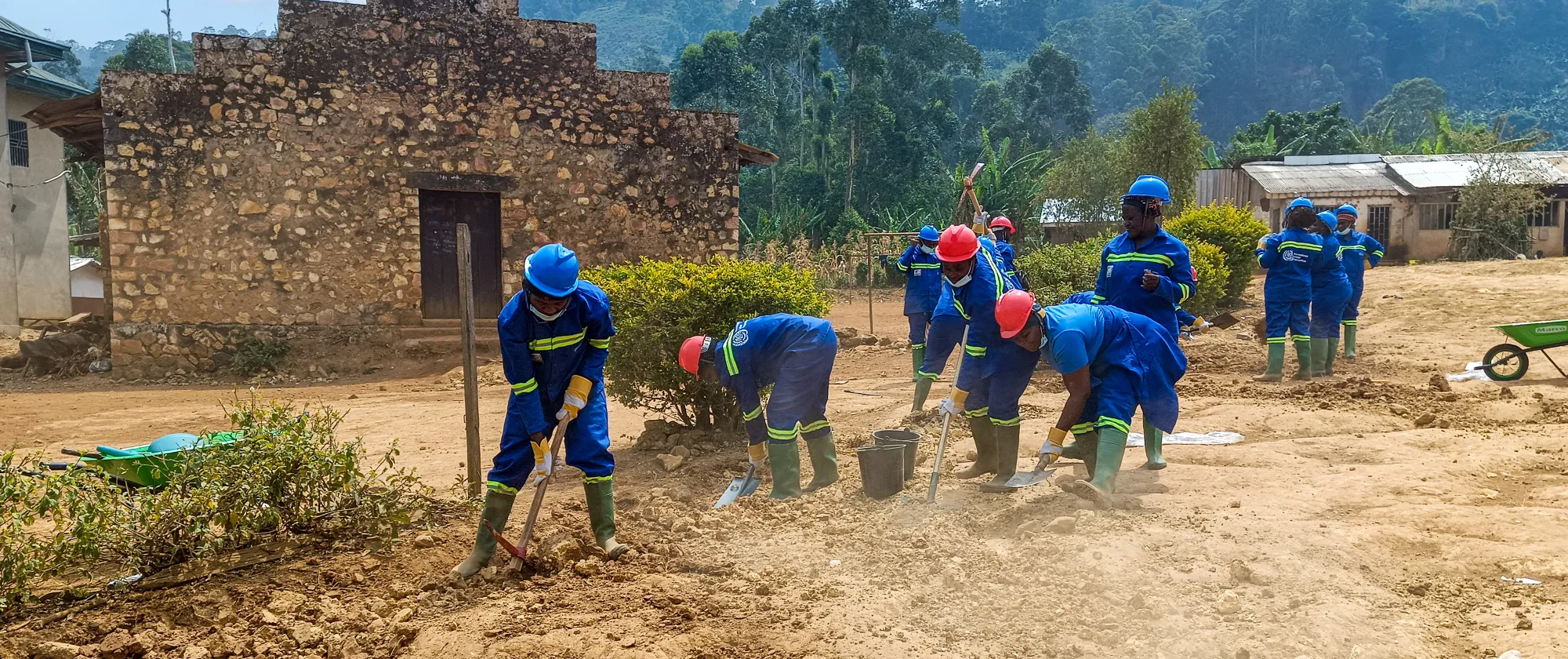 Female trainees in protective gear shape the roadside carriageway by hand at the Tubah training worksite.