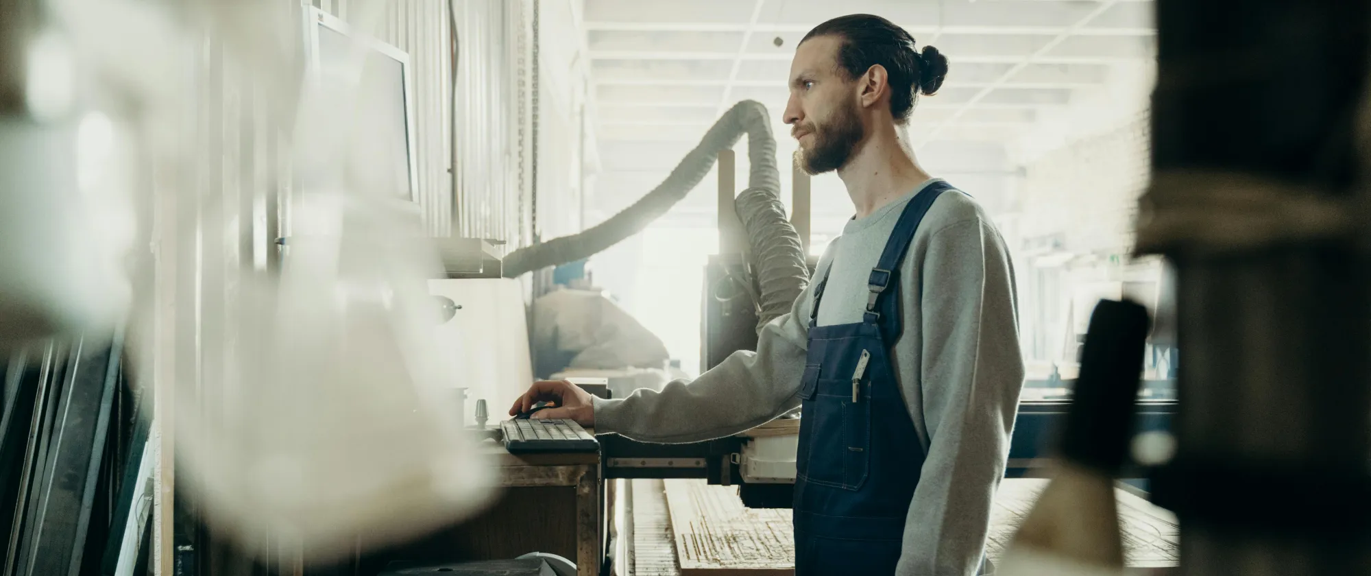 A factory worker stands in front of a computer