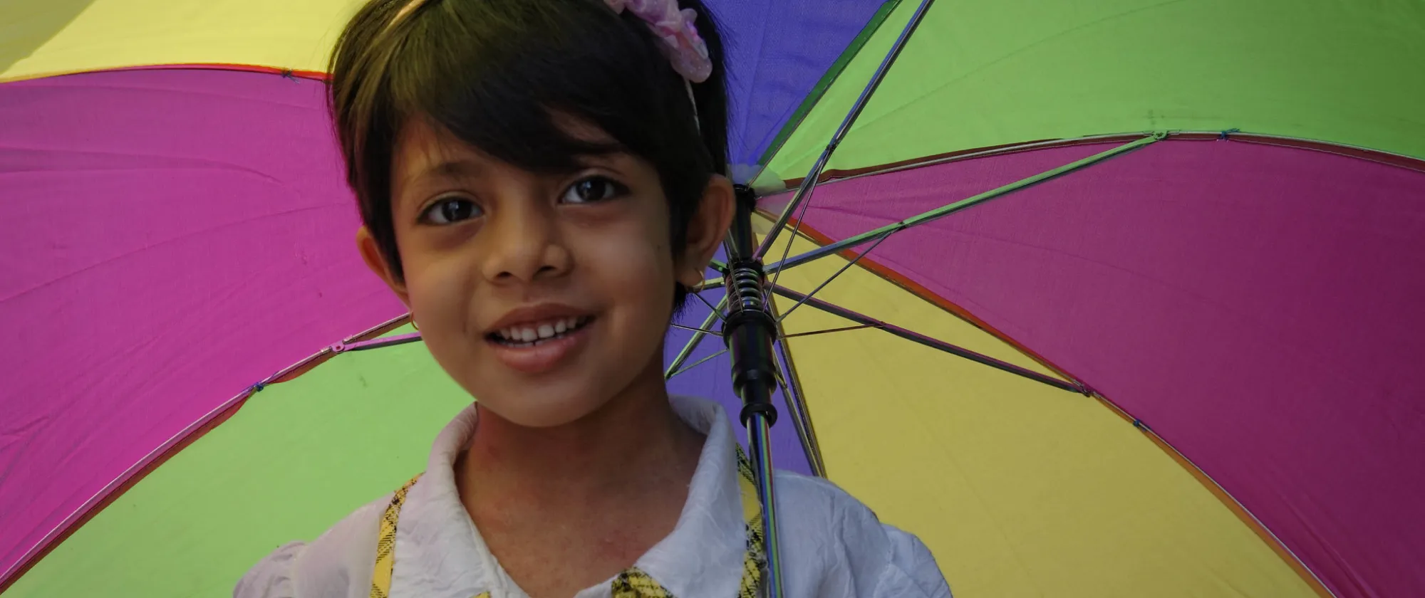 Portrait of a young girl holding a colourful umbrella. 
